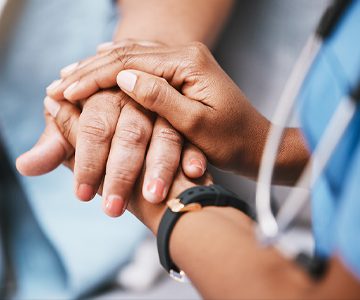 A nurse holding a patient's hand.